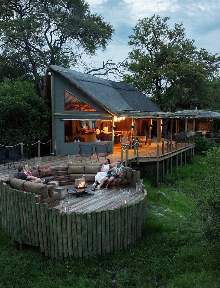 Guests around a fire pit on the deck of a Loko lodge at dusk